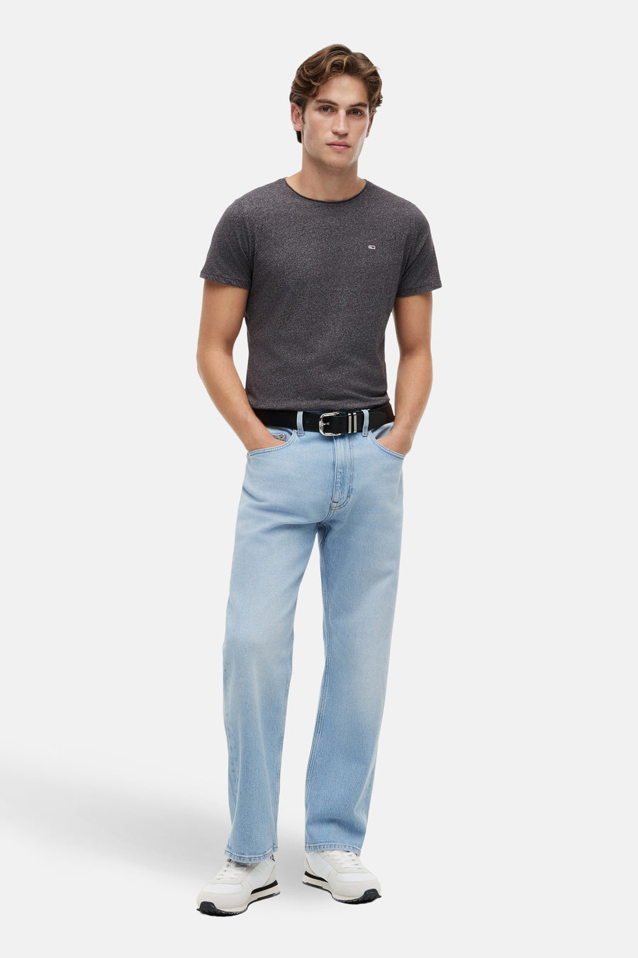 T-shirt noir de TOMMY JEANS, à manches courtes, combiné avec un jean bleu clair et des baskets blanches.
