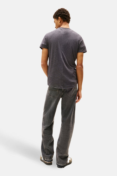 Achterkant van een man in een grijs T-shirt en jeans.