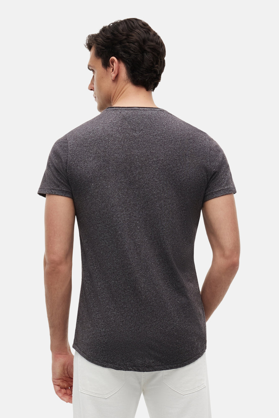 T-shirt noir chiné de TOMMY JEANS, vue de dos, manches courtes, col rond, texture légère, mannequin portant un pantalon blanc