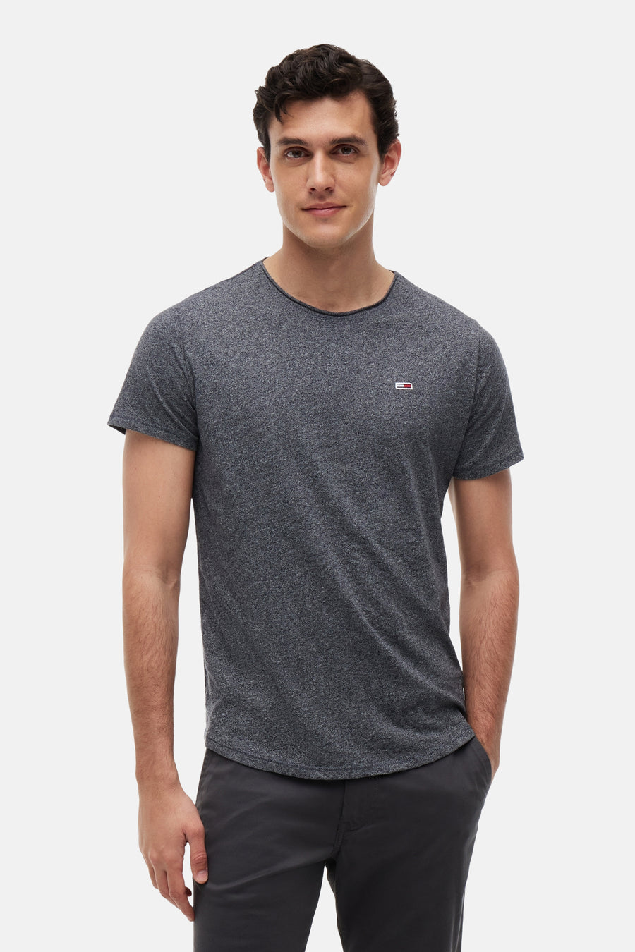T-shirt gris chiné TOMMY JEANS, avec petit logo rectangulaire sur la poitrine, porté par un homme.