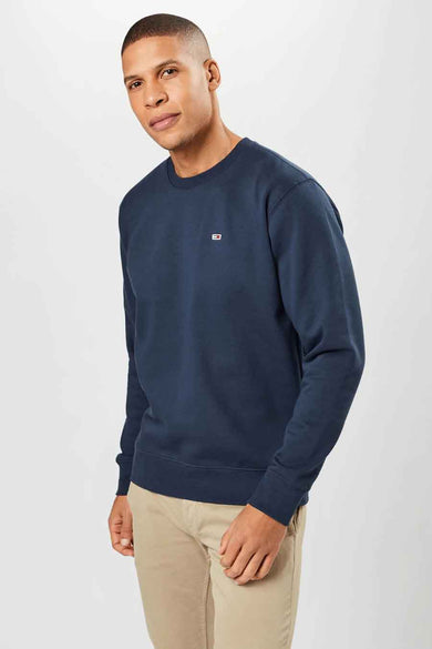 Pull-over bleu marine de TOMMY JEANS, avec col rond et design uni, associé à un pantalon beige.