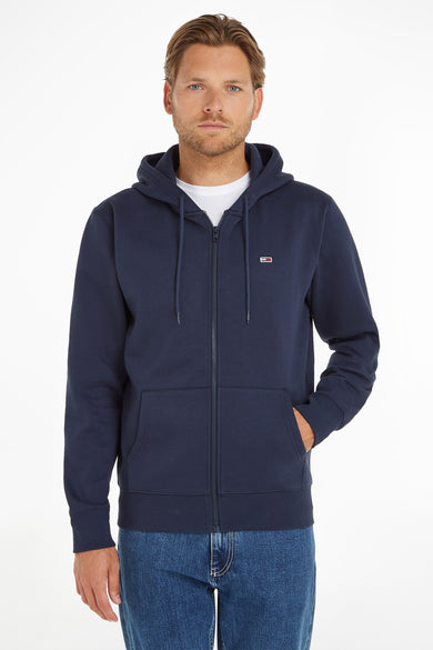 Pull-over bleu avec fermeture éclair de Tommy Jeans, avec capuche et une main dans la poche.