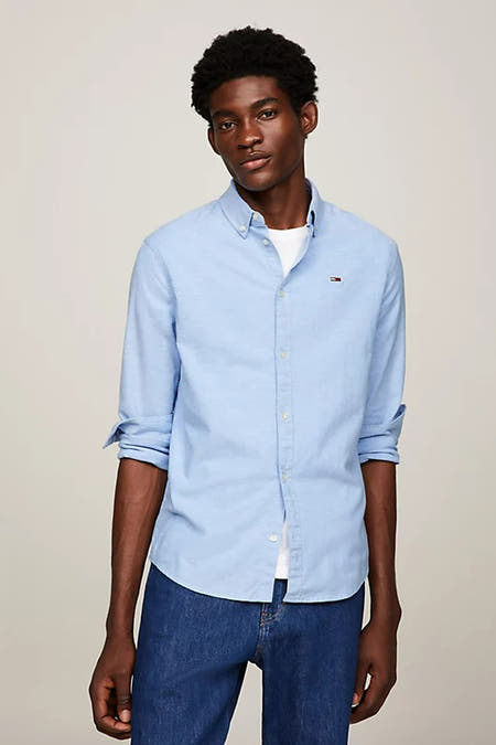 Chemise bleue à manches longues de TOMMY JEANS, portée avec un T-shirt blanc et des jeans foncés.