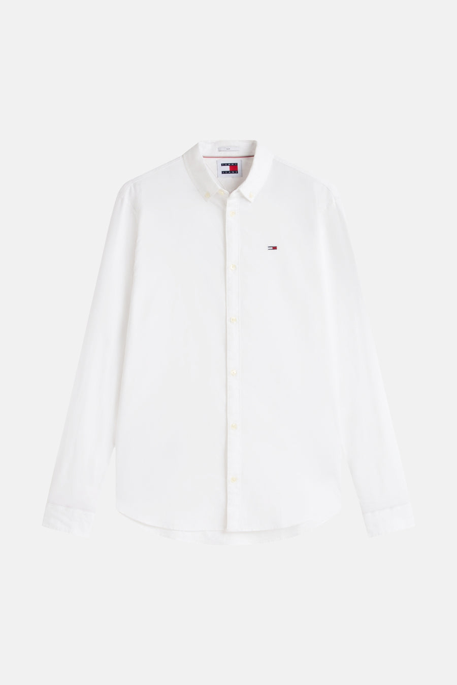Chemise blanche à manches longues Tommy Jeans, avec un petit badge de marque sur la poitrine.