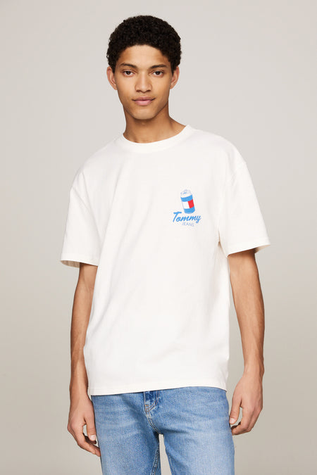 T-shirt écru à manches courtes de TOMMY JEANS, avec une petite impression sur la poitrine, porté avec un jean bleu.