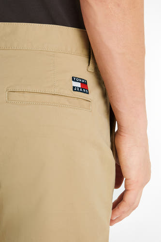 Short beige de TOMMY JEANS, avec une poche arrière et un patch logo, contre un fond blanc.