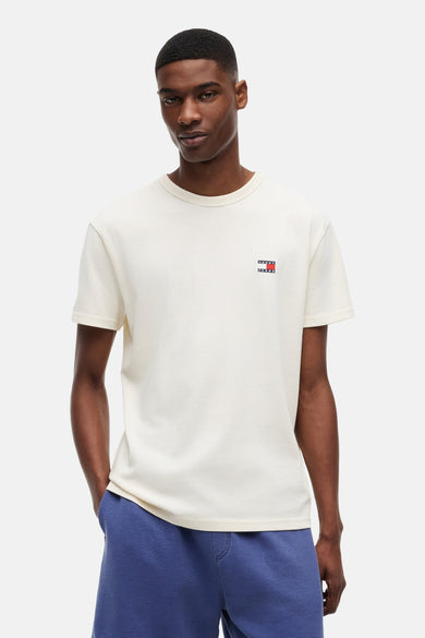 T-shirt jaune à manches courtes de TOMMY JEANS, avec petit logo drapeau sur la poitrine, porté par un homme en short bleu.