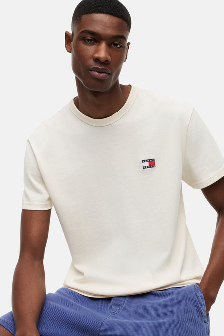Geel T-shirt met korte mouwen van TOMMY JEANS, met klein vlaglogo op de borst, gedragen door een man met blauwe shorts.
