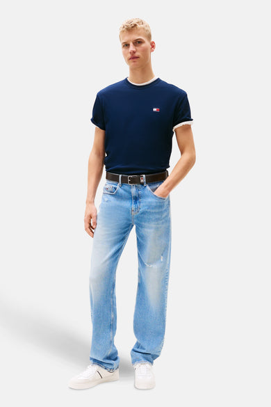 T-shirt bleu à manches courtes de TOMMY JEANS, avec un petit logo et porté avec des jeans et des baskets blanches.