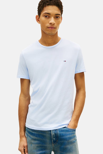T-shirt bleu à manches courtes de Tommy Jeans, associé à un pantalon en denim et des chaussures marron.