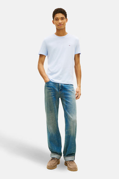 Blauw T-shirt met korte mouwen van Tommy Jeans, verder gecombineerd met een spijkerbroek en bruine schoenen.
