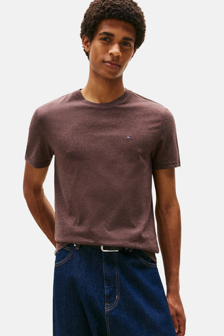 T-shirt brun à manches courtes de TOMMY JEANS, avec un petit logo sur la poitrine, associé à des jeans bleu marine et une ceinture.
