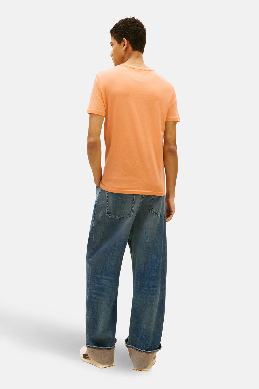 Oranje T-shirt met korte mouwen van TOMMY JEANS, met een relaxte pasvorm en gedragen met wijde jeans en sneakers.

