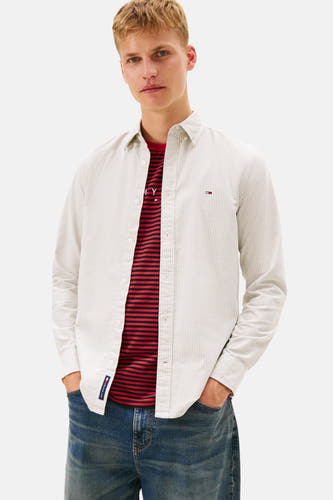 T-shirt Kaki à manches longues de TOMMY JEANS, avec des rayures discrètes et porté sur un t-shirt rayé rouge.