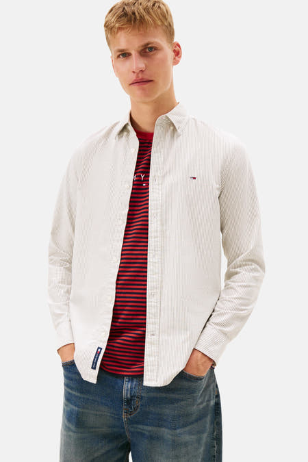 T-shirt Kaki à manches longues de TOMMY JEANS, avec des rayures discrètes et porté sur un t-shirt rayé rouge.