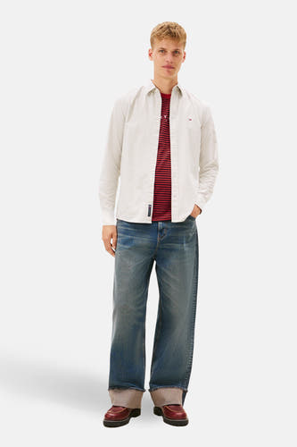 Kaki overhemd met lange mouwen van TOMMY JEANS, met subtiele strepen en gedragen over een rood gestreept shirt.