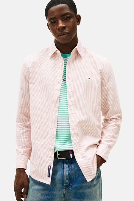 Chemise à carreaux rouge et blanche avec longues manches de TOMMY JEANS, portée sur une chemise à carreaux et associée à des jeans larges et des chaussures noires.