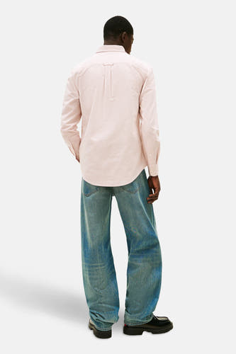 Chemise rayée rouge et blanche à manches longues de TOMMY JEANS, portée décontractée avec un jeans bleu et des chaussures noires.