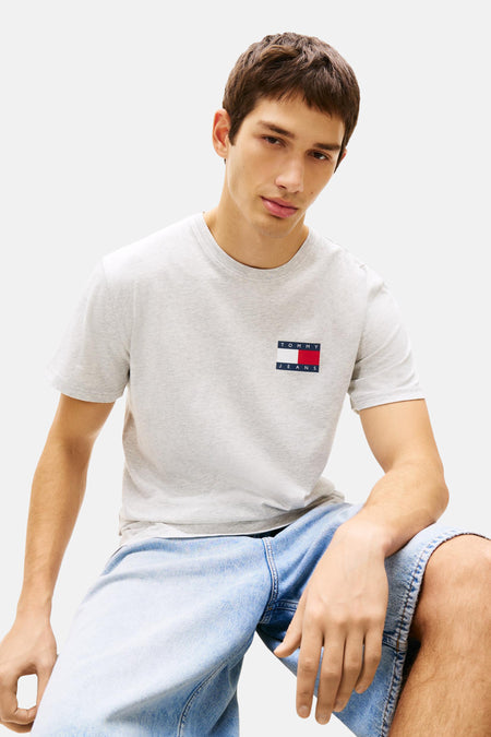 T-shirt gris à manches courtes de TOMMY JEANS, porté avec un short en jean.