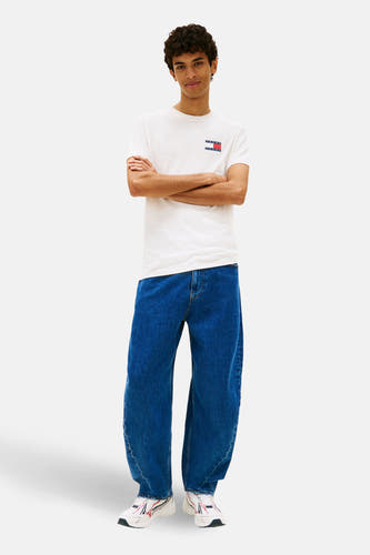 Wit T-shirt met korte mouwen van TOMMY JEANS, met logo op de borst, gecombineerd met wijde jeans en sneakers.
