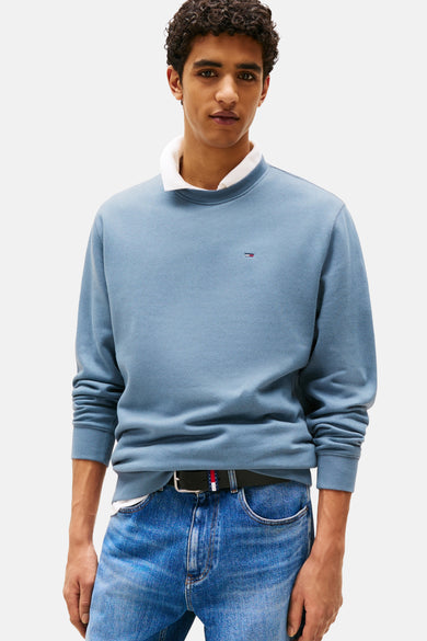Pull-over bleu de TOMMY JEANS, dos, avec col rond, associé à des jeans bleus et des baskets blanches.