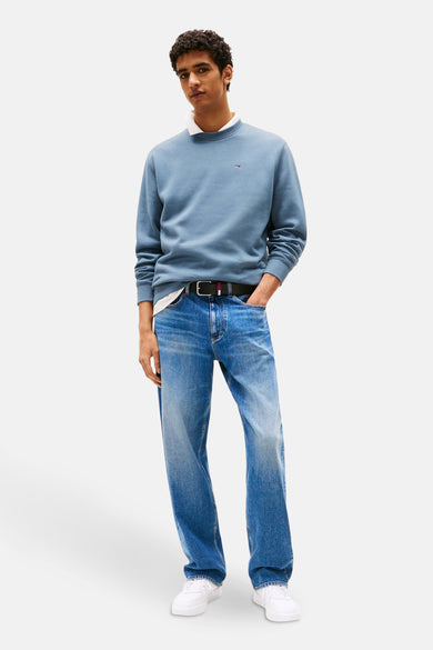 Pull-over bleu de TOMMY JEANS, porté sur un t-shirt blanc avec des jeans et des baskets blanches.
