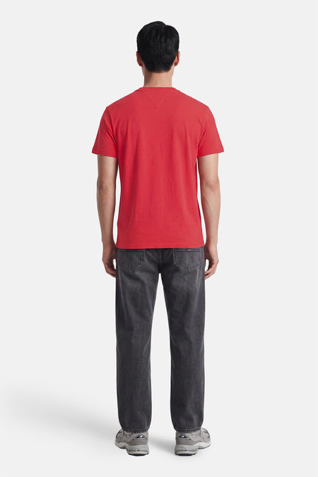Rode korte mouwen t-shirt van TOMMY JEANS, achterkant weergegeven, gladde stof, model draagt grijze jeans en sneakers