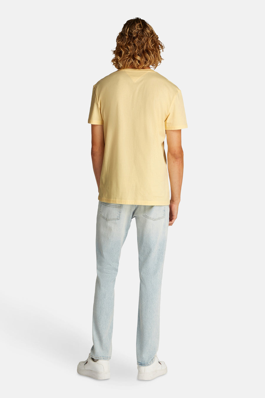 T-shirt jaune à manches courtes de TOMMY JEANS, porté avec un jean et des baskets blanches.