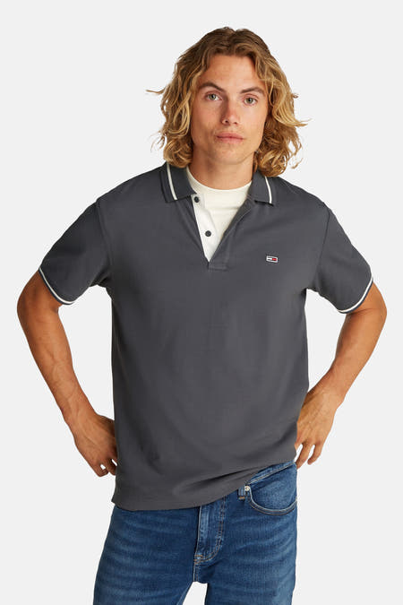 T-shirt gris à manches courtes de Tommy Jeans, avec une patte blanche le long du col et des manches.