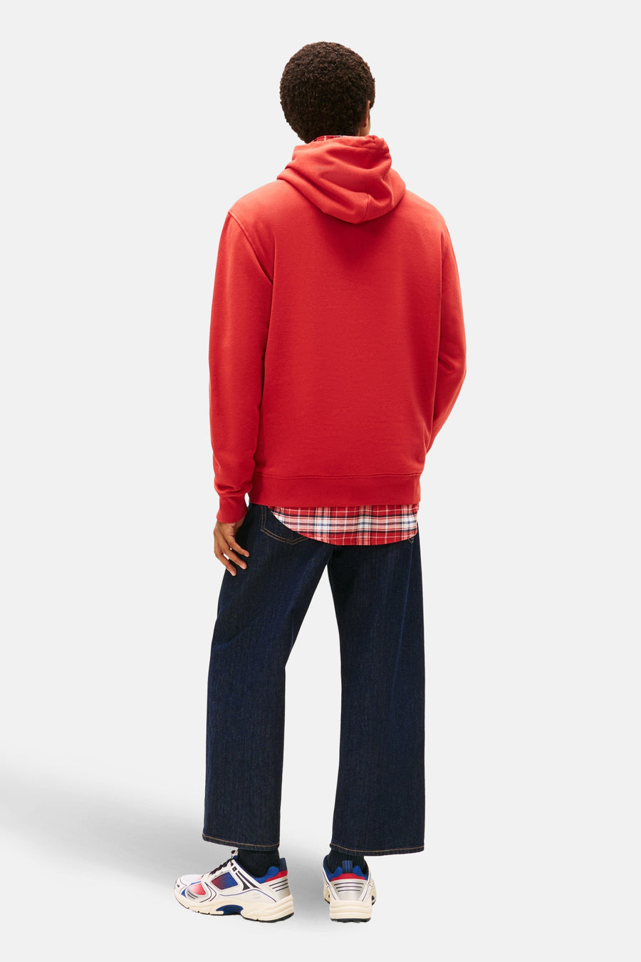 Pull-over rouge avec capuche de TOMMY JEANS, à longues manches et bordures côtelées, associé à un chemisier à carreaux et des jeans larges.