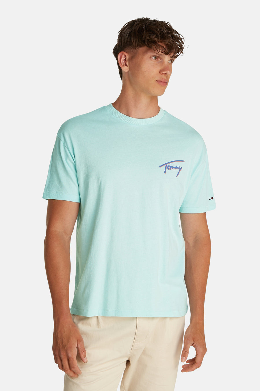 T-shirt turquoise à manches courtes de Tommy Jeans, avec petit logo de marque sur la poitrine et short beige court.
