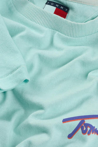 T-shirt turquoise à manches courtes de TOMMY JEANS, avec impression de logo en violet et rouge.