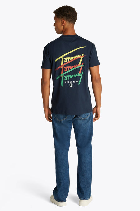 Blauw T-shirt met korte mouwen van TOMMY JEANS, met kleurrijke logo-opdruk op de rug, gecombineerd met jeans en witte schoenen.
