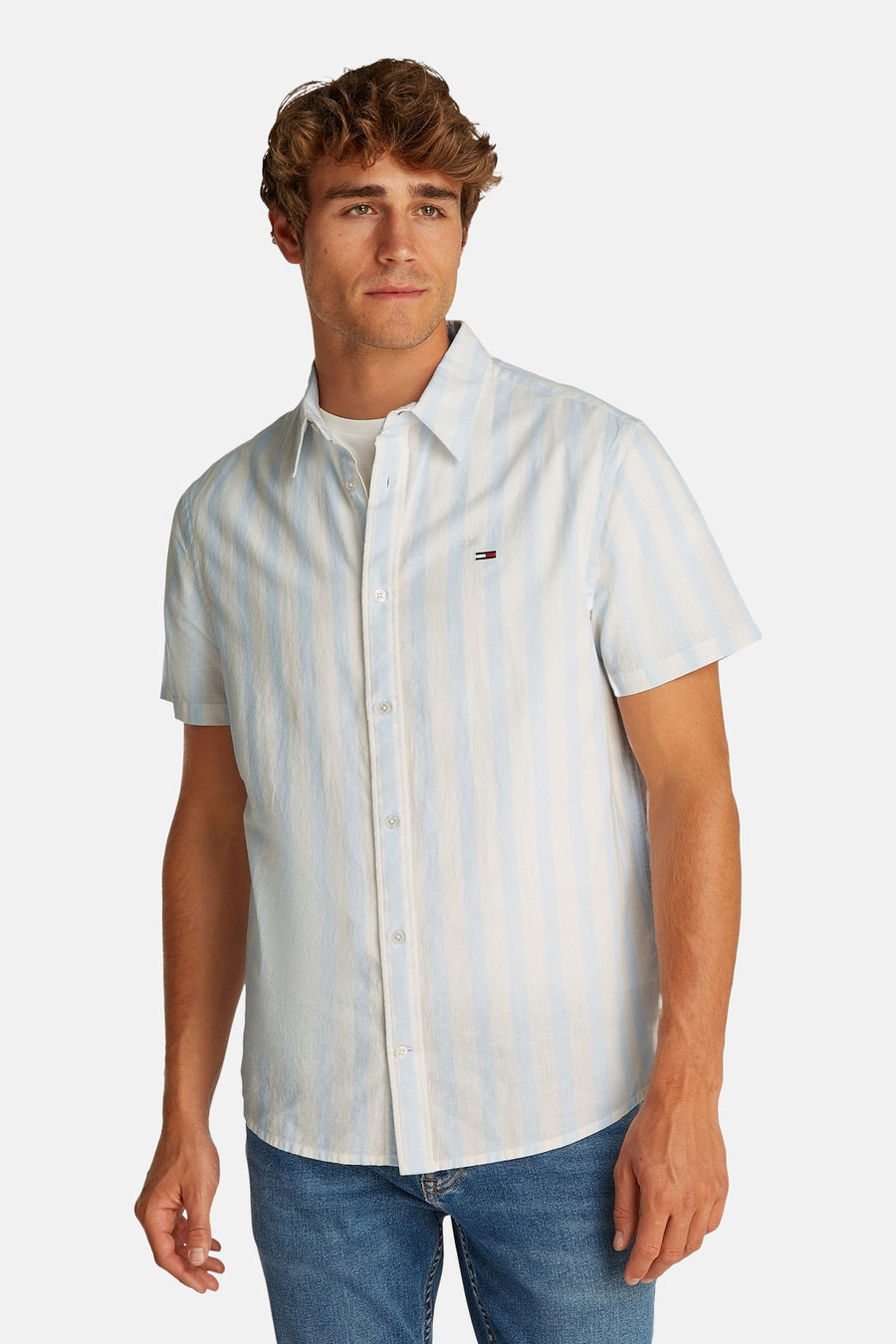 Chemise à rayures bleues avec manches courtes de TOMMY JEANS, avec col boutonné et un blason sur la poitrine.
