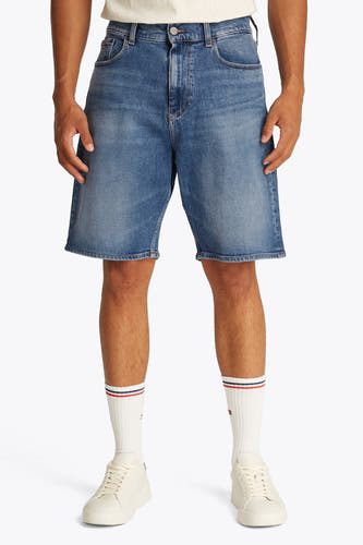 Jean court en denim bleu de TOMMY JEANS, porté avec des chaussettes blanches à rayures et des baskets crème.