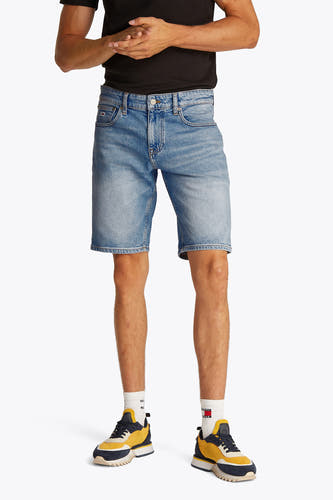 Jean court en denim bleu clair de TOMMY JEANS, avec des poches arrière et porté avec un T-shirt noir et des baskets colorées.