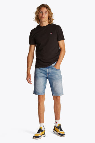 Jeansshort in lichtblauw denim van TOMMY JEANS, met een casual uitstraling en gecombineerd met een zwart T-shirt en kleurrijke sneakers.