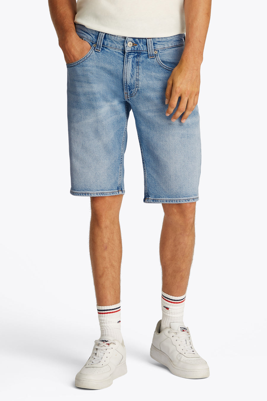 Jean court en denim bleu clair de TOMMY JEANS, porté avec des chaussettes blanches et des baskets.
