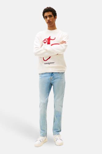Jean slim de Tommy Jeans en denim bleu clair, porté avec un pull blanc.