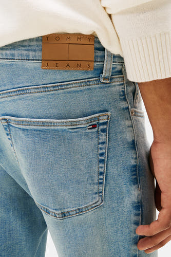 Jean slim de denim bleu clair de Tommy Jeans, avec étiquette de marque brun derrière.