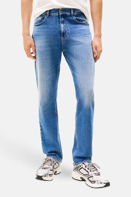 Jean slim fit en denim bleu de TOMMY JEANS, avec une légère décoloration et un léger lavage.