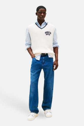 Jean droit en denim bleu marine de TOMMY JEANS, porté avec un chemisier rayé, une veste tricotée et des baskets blanches.