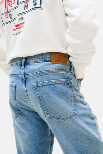 Jean droit en denim bleu clair de TOMMY JEANS, avec poche arrière et étiquette de marque.