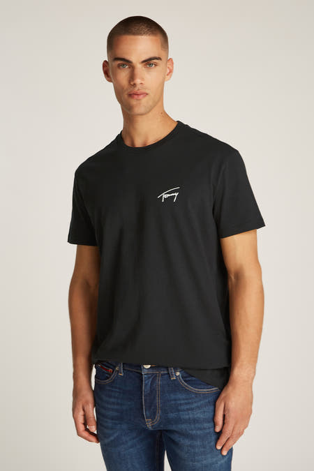 T-shirt noir à manches courtes de Tommy Jeans, avec un logo brodé sur la poitrine, porté avec un jean bleu.