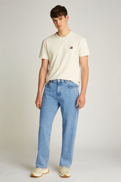 Rechte lichtblauwe denim jeans van TOMMY JEANS, gedragen met een crèmekleurig T-shirt en beige sneakers.