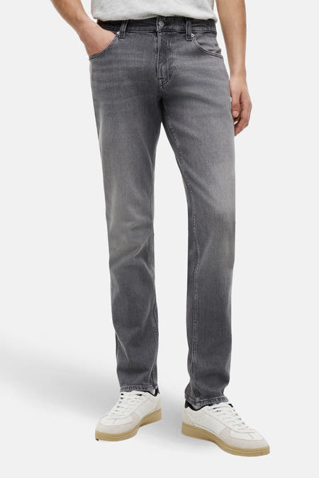 Jeans slim de couleur gris foncé en denim de TOMMY JEANS, avec un style décontracté et des baskets blanches.