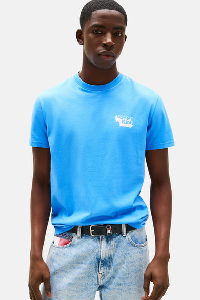 T-shirt bleu à manches courtes de TOMMY JEANS, vu de derrière, associé à des shorts en denim et à des chaussettes blanches avec des baskets.
