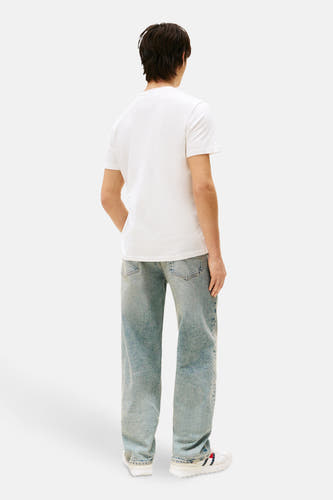 T-shirt écru à manches courtes de TOMMY JEANS, vu de dos, avec des jeans bleus et des baskets blanches.