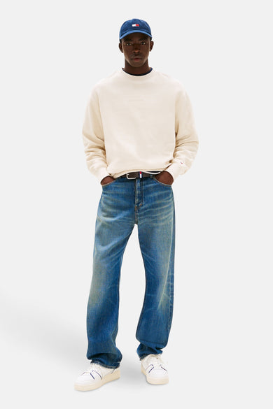 Gilet beige de TOMMY JEANS, avec une subtile texture à carreaux et porté avec des jeans larges et des baskets blanches.