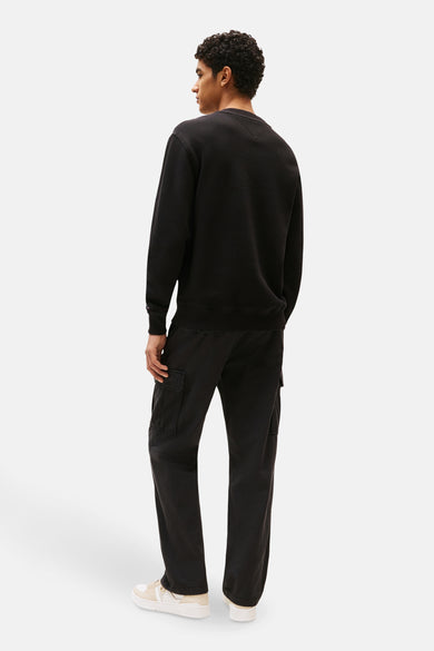 Man in zwarte trui en cargo broek met crèmekleurige sneakers.